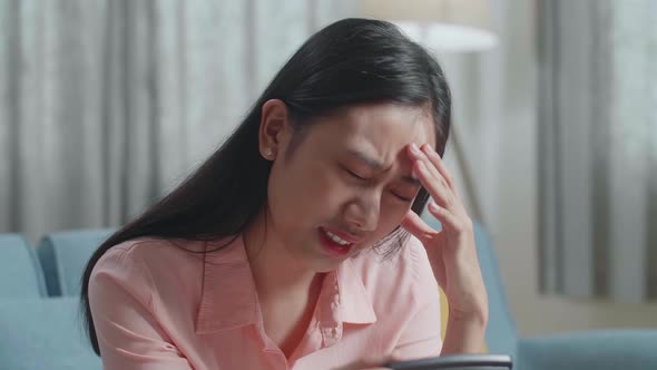 Close Up Of Asian Woman Holding Bill And Calculating Money By Calculator Then Having A Headache
