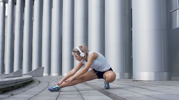 Beautiful female elegantly stretches leg muscles before jogging, warmup routine