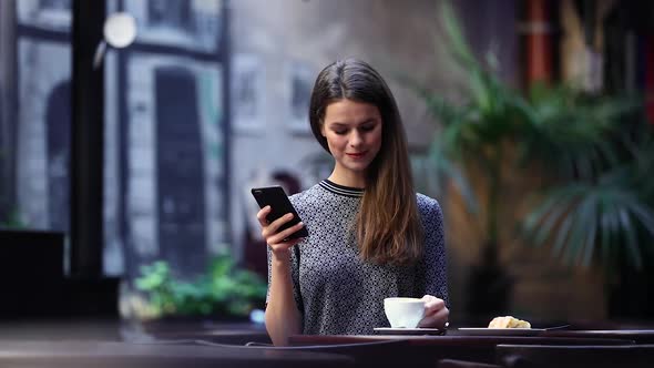 Woman With Mobile Phone Drinking Coffee In Cafe Portrait