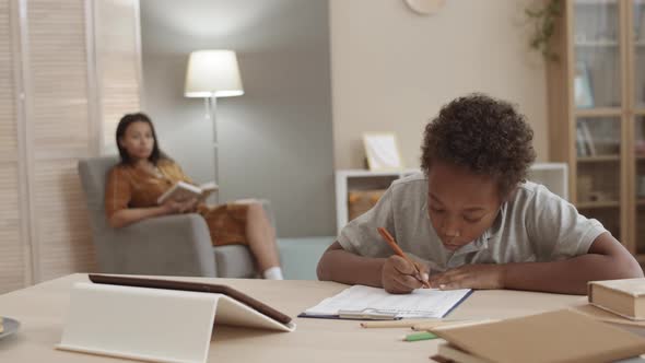 Kid Writing on Paper by Desk