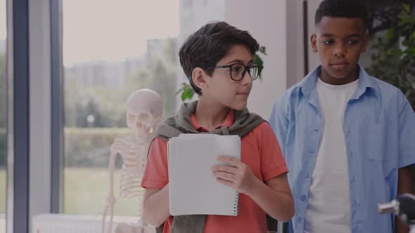 Elementary School Kid Listens Teacher and Joyfully Writing in Notebook in Class