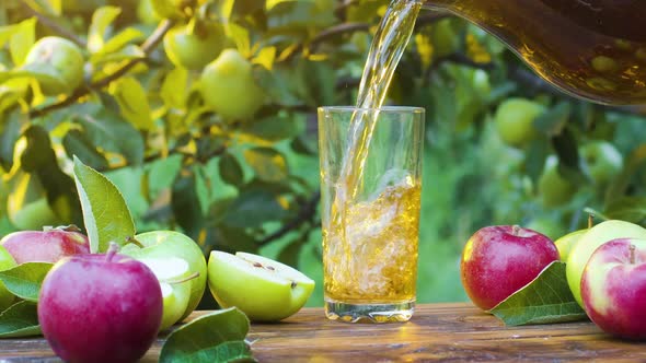 Apple juice is pouring from a decanter into a glas