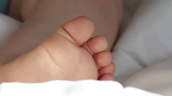 baby cute little feet on white blanket,sunny rays falls on toddler legs.baby boy falling asleep