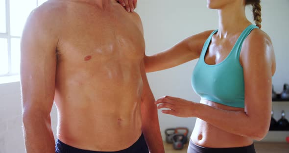 Smiling woman touching a muscular man in the gym