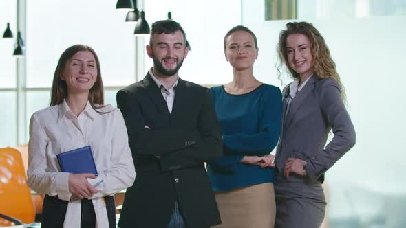 Group of Positive Confident Caucasian Women and Man Standing in Office Looking at Camera Smiling