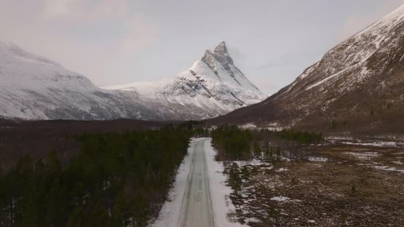 Winter road leading straight to Otertinden mountain in northern Norway. 4K aerial straight ascent d