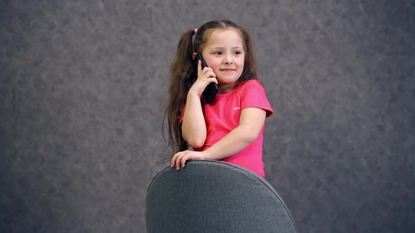 Little girl talking on phone. Portrait of little positive girl talking on cell phone