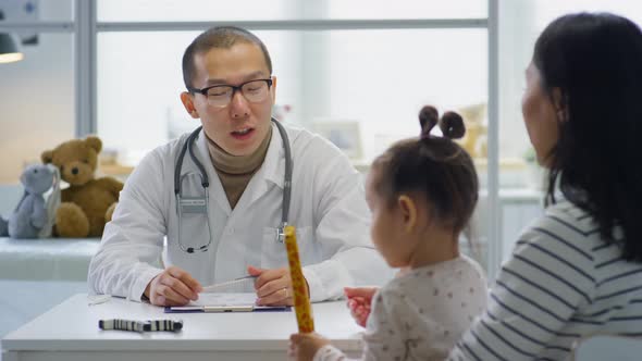 Asian Pediatrician Consulting Mother of Little Girl