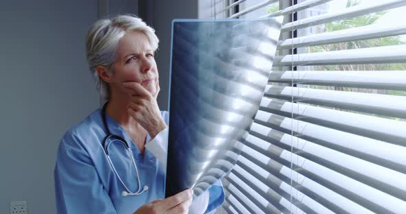Front view of mature Caucasian female doctor looking at x-ray report in hospital