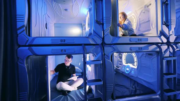 Young Man and Woman Inside of Pod Hotel Capsules