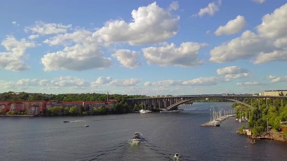 Aerial, drone shot, of boats at the sea, a bridge and houses on a sunny day, in Stockholm, Sweden