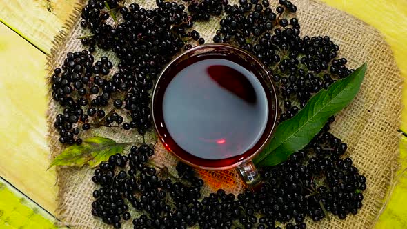 Close Up Red Black Berry Tea In A Cup Top View On A Wooden Vintage Table. Elderberry Tea. Vitamins