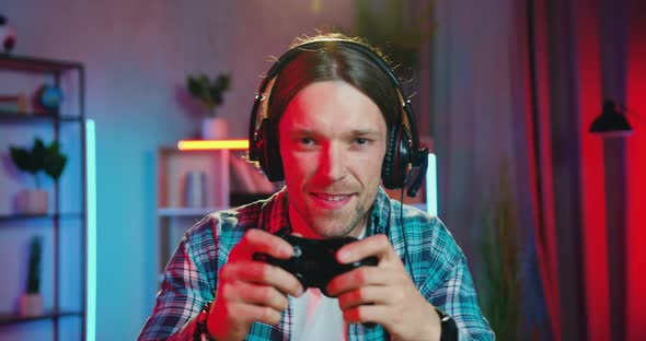 Gamer in Earphones which Enjoying His Victory in Video Games at Home in Contemporary Night Room