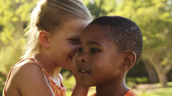 Girl whispering secret into boys ear