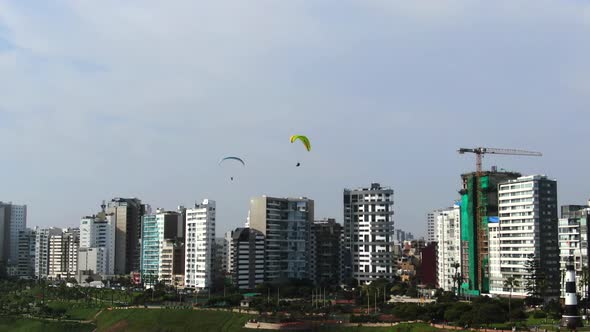 4k daytime aerial video of two paragliders flying over the city and coast in Miraflores, Lima, Peru