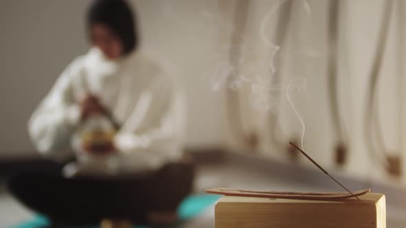 Smoldering Incense  a Woman Conducting a Ritual Before Meditation in the Background