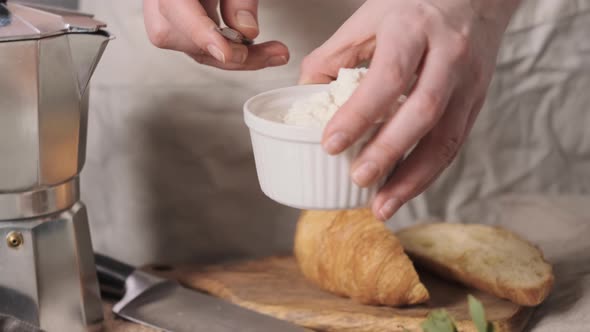 Woman Takes Soft Cheese From Bowl with Knife