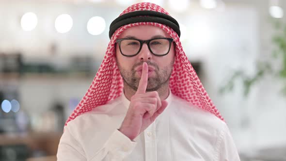 Young Arab Businessman Putting Finger on Lips 