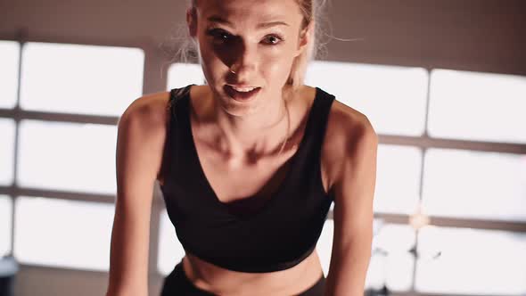 Young Fit Sporty Blone Girl Exercising on a Bike at Gym