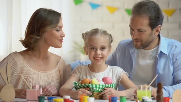 Caring Parents Kissing Little Daughter