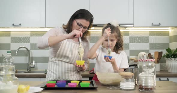 Mother and Daughter Child 9, 10 Years Old Preparing Cupcakes Together at Home in Kitchen