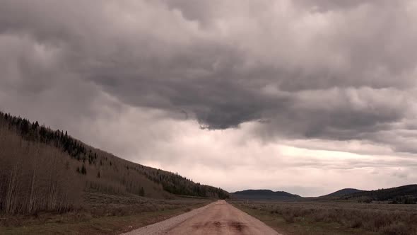 View of storm clouds building over dirt road