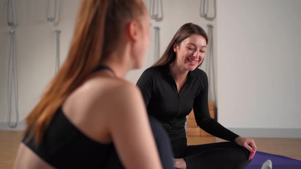 Two athletic women are resting after yoga training and chatting. Workout for health