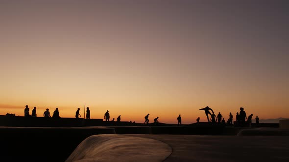 Silhouette of Young Jumping Skateboarder Riding Longboard, Summer Sunset Background. Venice Ocean