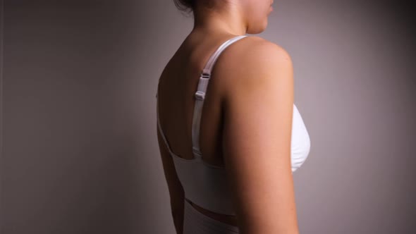 Female Wear A White Support Bra Turning Slowly Around Post Breast Augmentation Surgery. - Close up