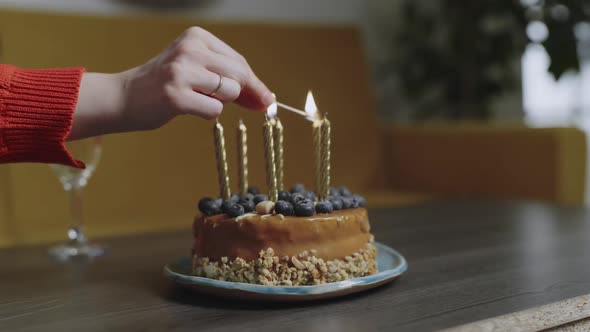 Female Hands Light Candles on the Birthday Cake at Home Close Up