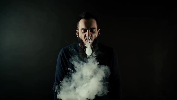 Bearded Man Making Many Small Ring Circles of Steam with Electronic Cigarette