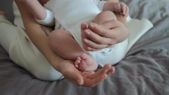 Baby feet in mother hands with tattoo. Mom and her Child.