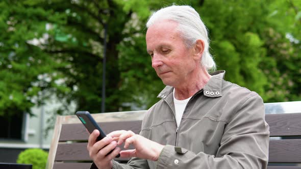 A Portrait of an Elderly Person Using a Mobile Phone Holding Device Text Messages Surfing on the