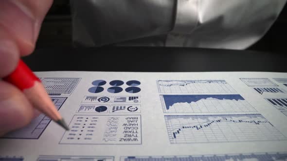 Accountant analyzing business marketing data on paper dashboard at office table.