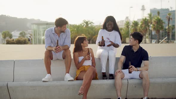 Young Happy Multiracial Friends Drinking Cold Beer at Sunset on Seafront