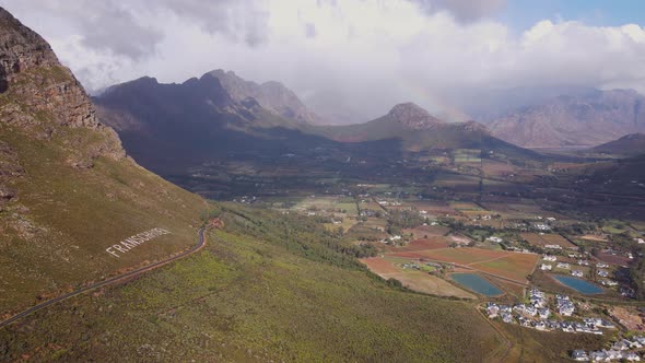 Aerial arc on mountainside, scenic road overlooking fertile Franschhoek valley