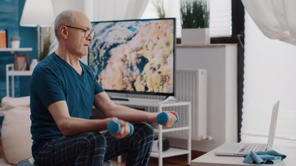 Man Lifting Dumbbells While Sitting on Fitness Toning Ball