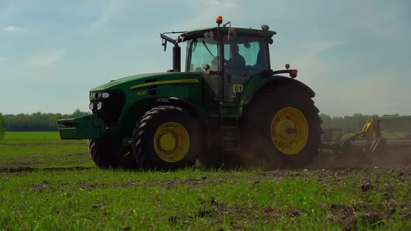 Tractor plows the ground with a plow in the field