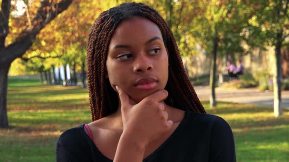 Young Beautiful Black Woman Thinks About Something in Autumn Park