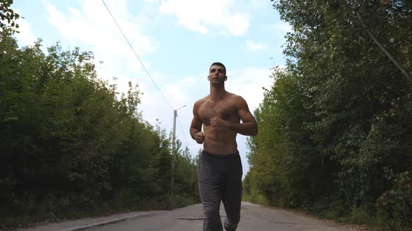 Handsome Sportsman Sprinting Fast Along Road with Beautiful Landscape at Background