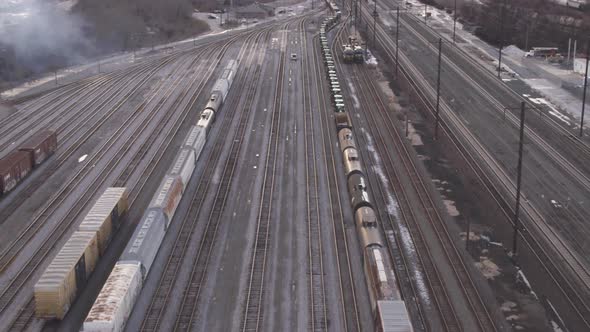 Aerial view of a long train of rail cars pulling away from a train yard