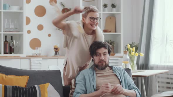 Happy Couple Playing and Fighting for Smartphone on Couch at Home