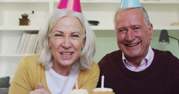 Portrait of happy senior caucasian couple celebrating a birthday making a video call