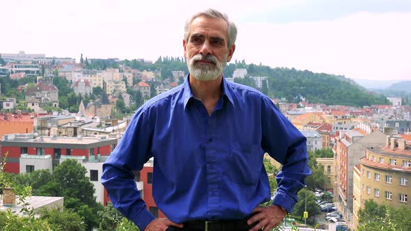 Old Senior Man Looks Around - City (Buildings) in Background