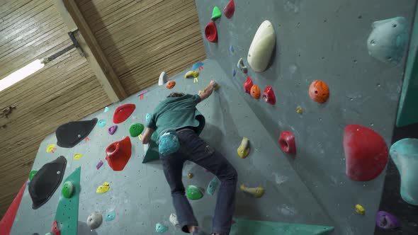 Man Climbs the Wall Training on a Climbing Wall Practicing Rockclimbing Mountaineer Training