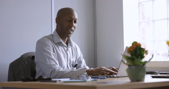 Businessman sitting in office using laptop and smartphone