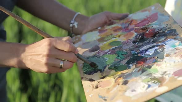 Girl artist paints a picture with oil paints. Beautiful place to relax