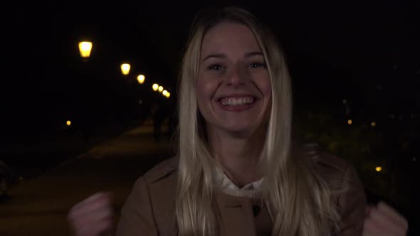 A Young Beautiful Woman Celebrates in an Urban Area at Night