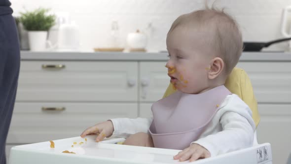 Father Feeding His Baby in the Kitchen at Home Closeup of Oneyearold Baby Boy in White High Baby