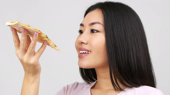 Happy Asian Lady Eating Pizza Slice Posing Over White Background